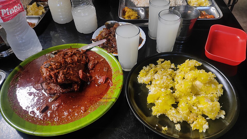 Traditional Kerala toddy shop spread — spicy fish curry, tapioca, and sides served on a banana leaf