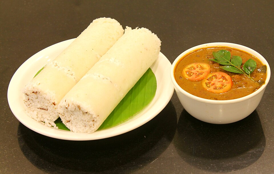 Traditional Malabar breakfast of steaming puttu served alongside flavorful black kadala curry